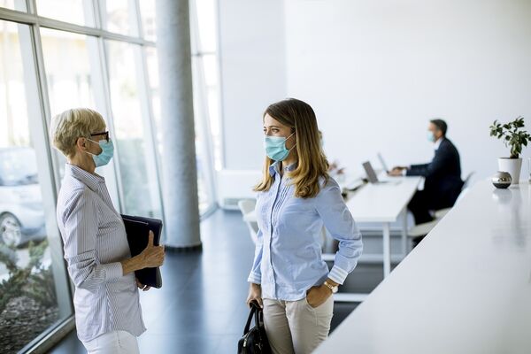 Frauen tragen Masken im Büro zum Schutz vor Corona